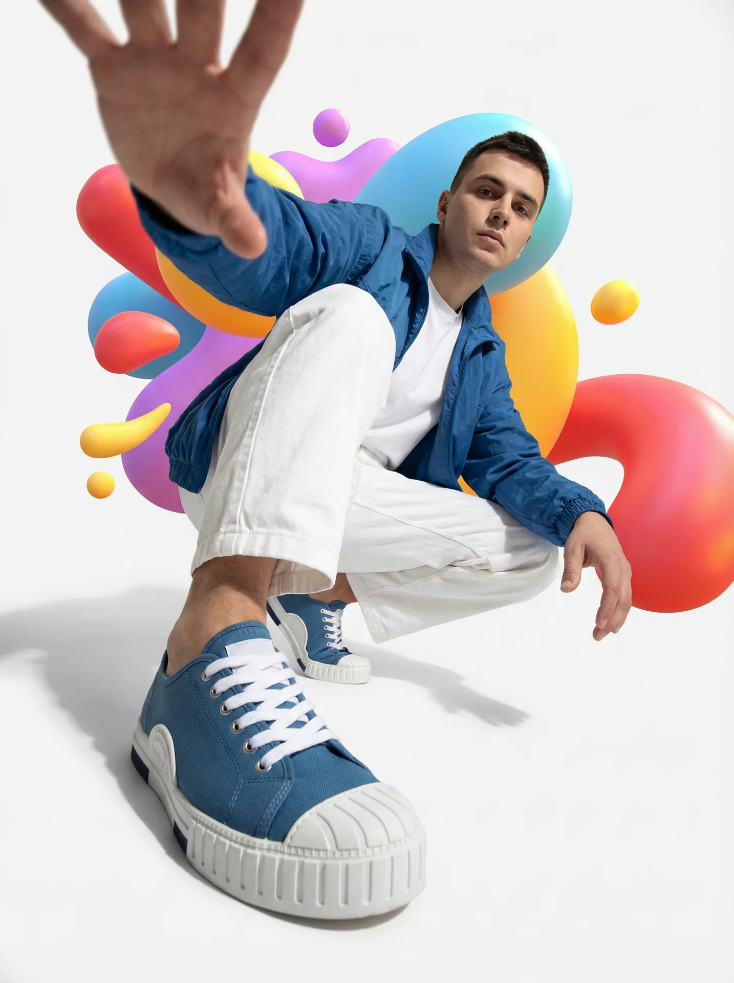 Fashion editorial: young man crouched at a wide-angle lens, hand toward the camera
